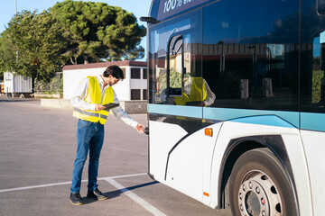 Quality supervisor performing a daily inspection on a public electric bus, ensuring compliance and maintenance standards before service