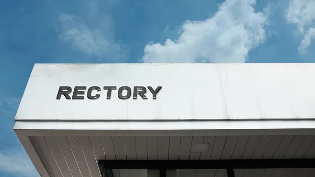 Rectory word sign displayed on a religious or administrative building under a clear blue sky, symbolizing church residence, clerical office, spiritual community, and parochial authority