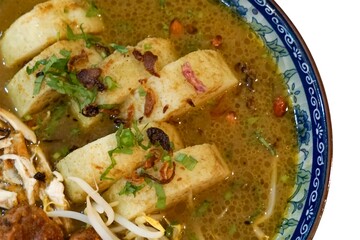 Authentic Soto Ayam served in a decorative bowl with shredded chicken, potatoes, bergedil, bean sprouts, and garnishes in rich chicken broth.