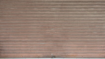 Old red rusty steel rolling door of a shop, peeling paint, scratches, steel rolling door background, red metal rolling door background, background and texture image.