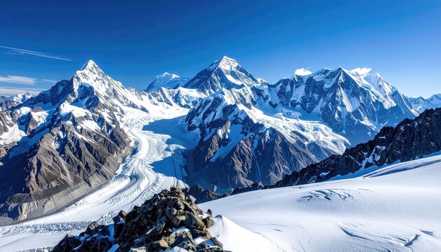 Majestic snow covered mountain range under a clear blue sky with bright sunlight illuminating the rugged peaks and glaciers a vast wilderness landscape