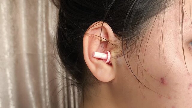 Young brunette girl with earplugs in her ears close-up. Sleep in silence. Protection from noise, noisy neighbors