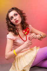 Funny Portrait of Young Caucasian Female Posing in Colorful Clothing Holding Lollipop Candy in Dolly Style Against Color Background.