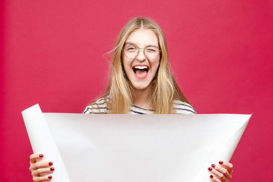 One Laughing Winsome Caucasian Young Blond Girl In Glasses Posing With White Advertising Copy Space Rolling Paper List Over Trendy Burgundy Background
