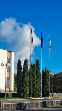 Flags of Ukraine, the European Union, and the city of Varash/RNPP on flagpoles. A symbol of independence, European integration, and local identity