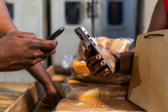 Customer makes mobile money payment at bread bakery using smartphone, showcasing fintech, contactless and cashless transactions in Africa