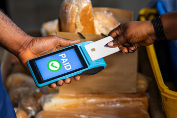 Contactless payment in Africa. Customer makes successful transaction using point of sale, POS terminal at a local bakery