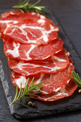 Coppa slices with rosemary and peppercorns on slate plate