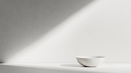 empty white ceramic bowl rests on a pristine table in a minimalist setting with a striking diagonal shadow, perfect for product photography or abstract design.