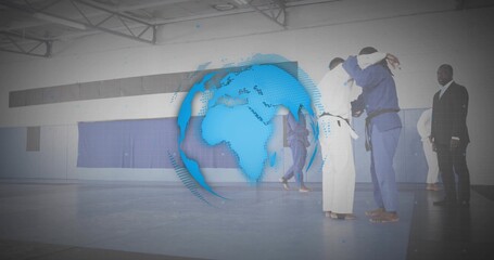 Grappling pair of martial artists practicing judo on blue mats at gymnasium, with digital globe
