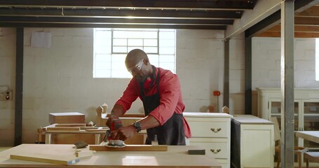 Sanding mature carpenter wearing apron smoothing wooden plank at carpentry shop, sander, lumber