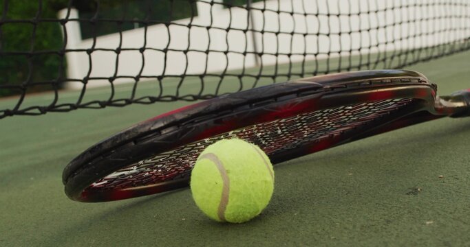 Fototapeta Displaying tennis racket and tennis ball on outdoor hard court, with taut tennis net background