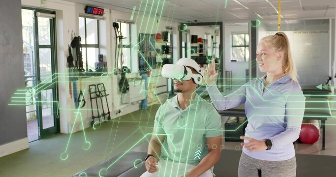Female trainer in leggings guiding seated male client using VR headset in rehab room, AR overlay