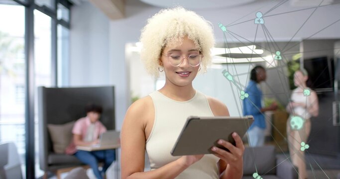 Holding woman with glasses in sleeveless beige top using tablet in office, with network overlay - Powered by Adobe