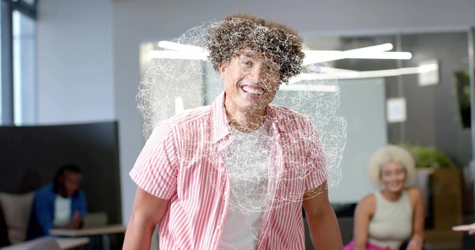 Smiling man wearing pink-striped shirt standing in office lounge, with digital swirl overlay