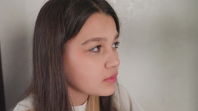 Side view shows beautiful young girl with long hair staring in silence, poised before muttering word, calm profile under soft indoor light, subtle eyelash detail, neutral wall background, quiet mood