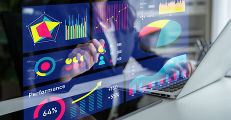 A business professional engages with data visualization charts and graphs on a touchscreen laptop, showcasing analysis and performance metrics in a modern office setting. Impute