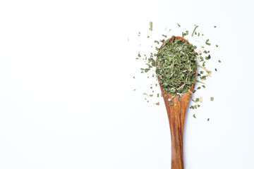 dried and chopped parsley in a wooden spoon, top view