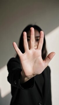 A woman standing with her hand open facing the camera, stop sign with hand, no measn no