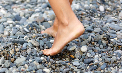 A woman's foot is on a rocky beach