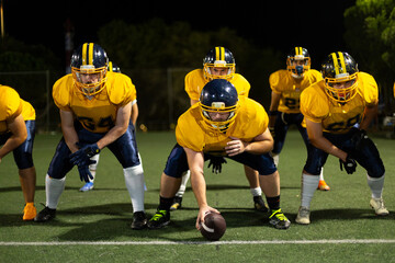 American football players lining up for scrimmage at night