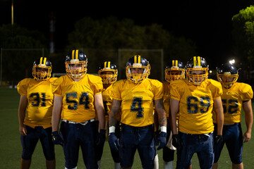 American football players standing together on night field