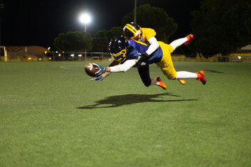 American football players diving for ball during night game