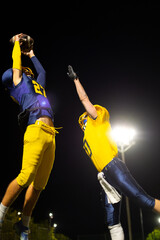 American football receiver making a touchdown catch at night