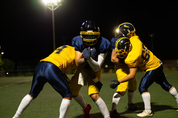 American football players tackling during night game