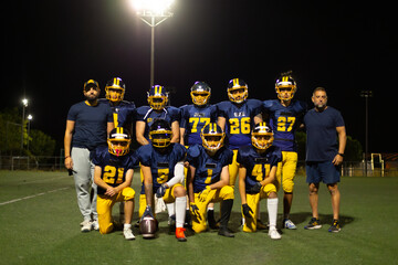 American football team and coaches posing on field