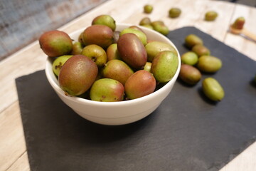 Hardy kiwi berries in white bowl on slate serving board