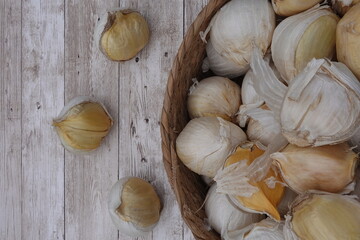 Garlic bulbs in rustic basket on wooden background