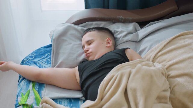 Plump kid stretching gently on bed while opening eyes under beige blanket in cozy bedroom with daylight streaming through window creating relaxed calm peaceful atmosphere of morning rest