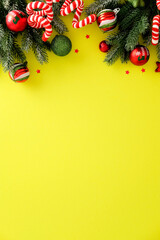 Christmas top border with pine, candy canes, baubles and red stars on yellow background. Bright festive layout with copy space for seasonal design.