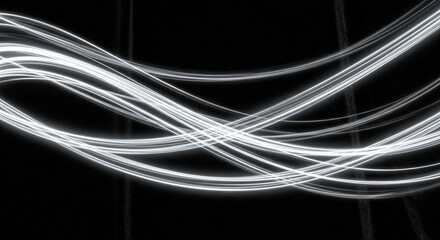 Abstract light streaks dance across a dark void, creating a mesmerizing display of motion and energy, evoking a sense of futuristic technology and ethereal beauty.