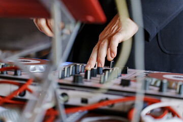 Hands adjusting DJ equipment during a lively party