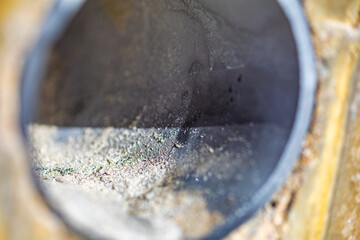 A round metal pipe on a yellow surface, illuminated by the sun.
