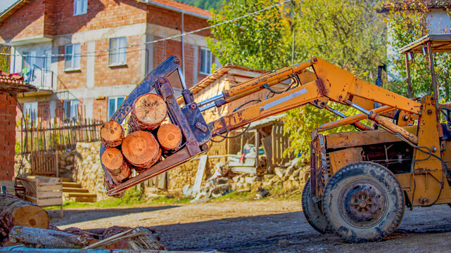 Loader carrying firewood logs in rural village - Powered by Adobe