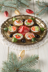 Close-up of New Year's sandwiches with cream cheese and vegetables in the shape of Christmas balls on a plate on a table. Vertical