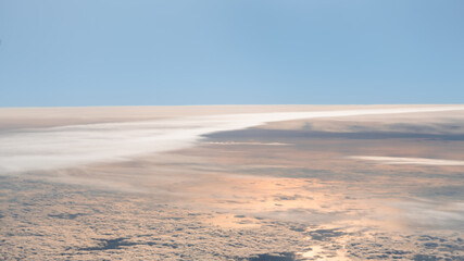 view from the airplane window to mountains clouds and blue sky