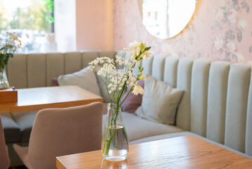 The cozy interior of the cafe and the delicate flowers create an atmosphere of tranquility and elegance.