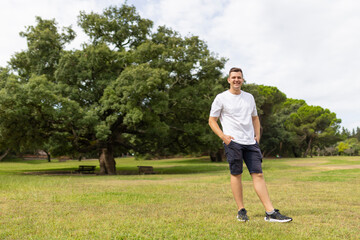 Young smiling man standing in green park