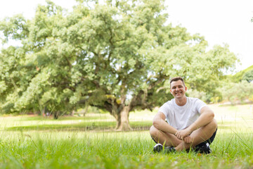 Obraz premium Man smiling, relaxing outdoors on grass in a park