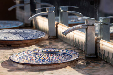 Close up of the Moroccoan traditional bathroom sink in restroom in restaurant or hotel or shopping mall, interior decoration design. Row of the Moroccan ceramic wash basin in public toilet. 