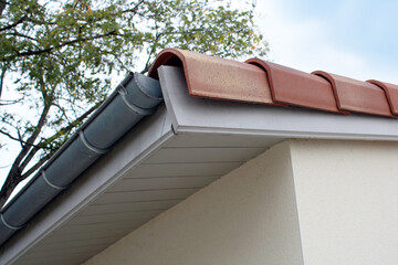 Gouttière zinc gris sur la façade de la maison, descentes rondes et sous-face en lambris bois