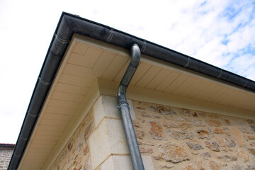 Gouttière zinc gris sur la façade de la maison, descentes rondes et sous-face en lambris bois