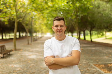 Fototapeta premium Young man smiling with crossed arms in park