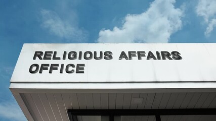 A Religious Affairs Office word sign displayed on a governmental or civic building under a clear blue sky, symbolizing state administration, official policy, community faith, ecclesiastical services