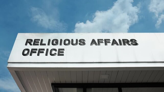 A Religious Affairs Office word sign displayed on a governmental or civic building under a clear blue sky, symbolizing state administration, official policy, community faith, ecclesiastical services