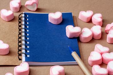 sweet heart shape of marshmallows with note book on wooden background